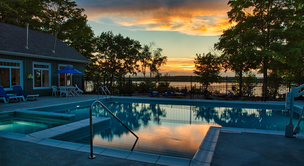 Sunset view of the Sandbank Summer Village's outdoor leisure pool with lakeside views
